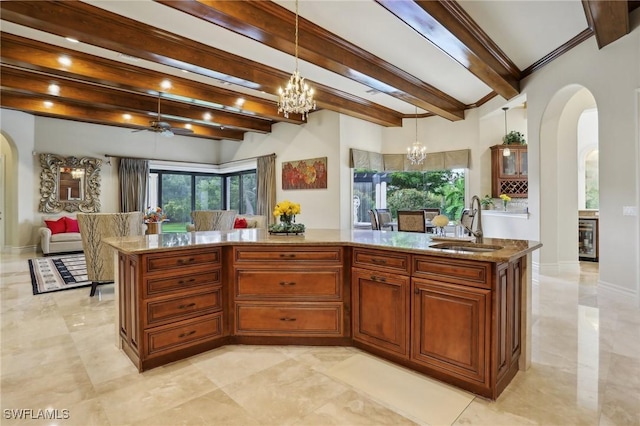 kitchen featuring sink, light stone counters, a center island with sink, pendant lighting, and ceiling fan with notable chandelier