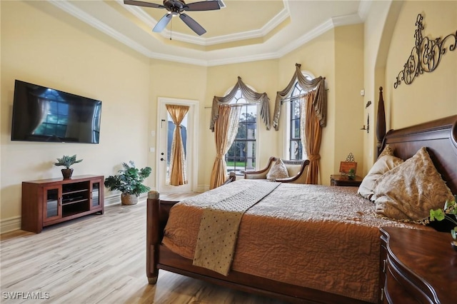 bedroom featuring light hardwood / wood-style flooring, ornamental molding, a raised ceiling, and ceiling fan