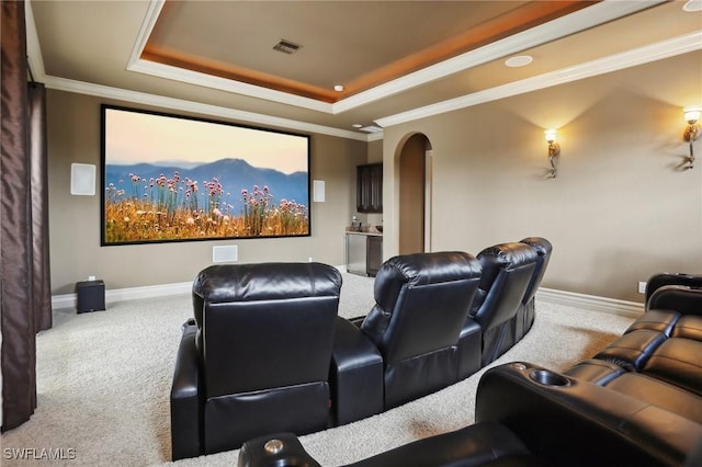 cinema room featuring ornamental molding, a raised ceiling, and carpet