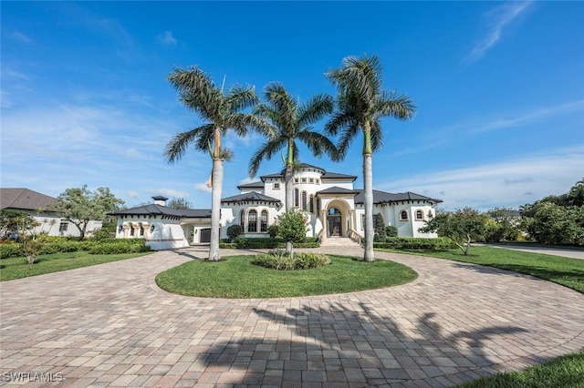 mediterranean / spanish house featuring a front yard, an attached garage, and curved driveway