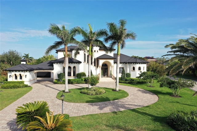 view of front facade featuring a front yard, stucco siding, and curved driveway