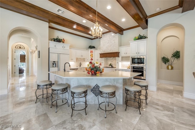 kitchen with built in appliances, marble finish floor, a sink, and premium range hood