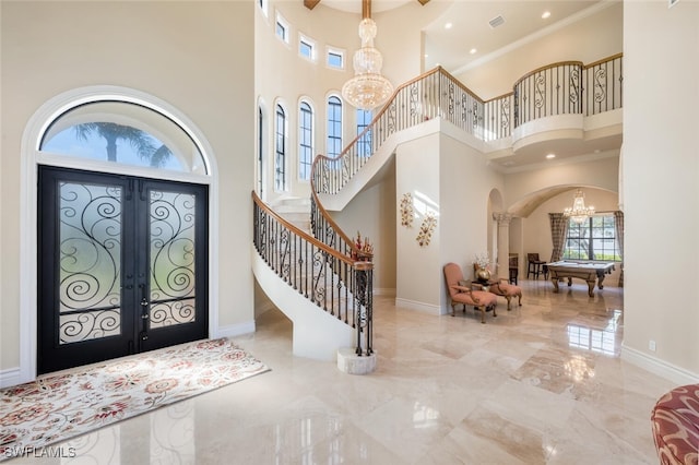 foyer entrance featuring a notable chandelier, marble finish floor, french doors, arched walkways, and stairway