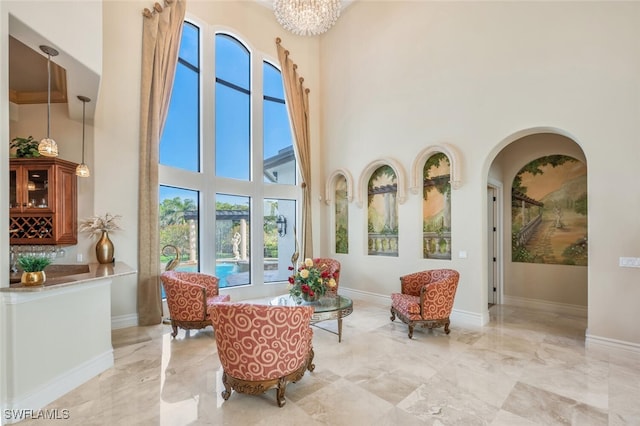 sitting room featuring baseboards, marble finish floor, and a towering ceiling