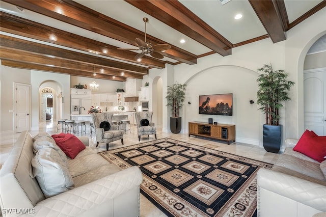 living area featuring arched walkways, baseboards, a ceiling fan, and ornamental molding