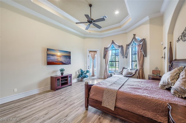 bedroom with visible vents, crown molding, baseboards, wood finished floors, and a raised ceiling