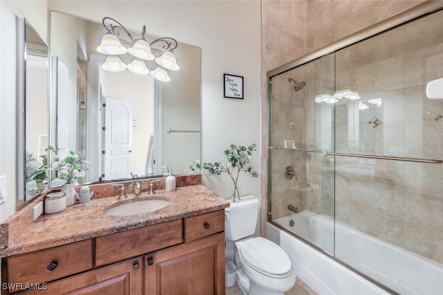 bathroom with vanity, toilet, and bath / shower combo with glass door