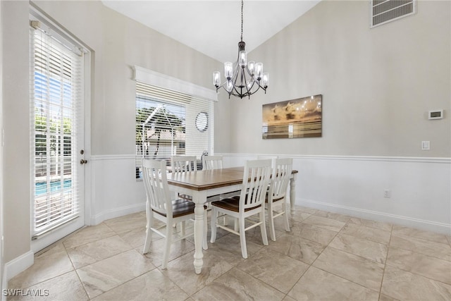 dining room with light tile patterned floors, a chandelier, and lofted ceiling