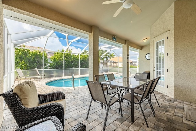 view of pool with ceiling fan, glass enclosure, and a patio