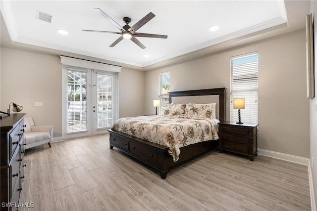 bedroom featuring light hardwood / wood-style flooring, french doors, access to outside, a tray ceiling, and ceiling fan