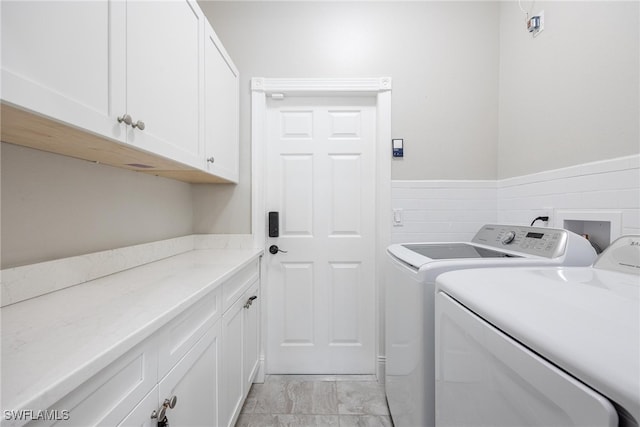 washroom featuring washer and dryer, cabinets, and light tile patterned floors