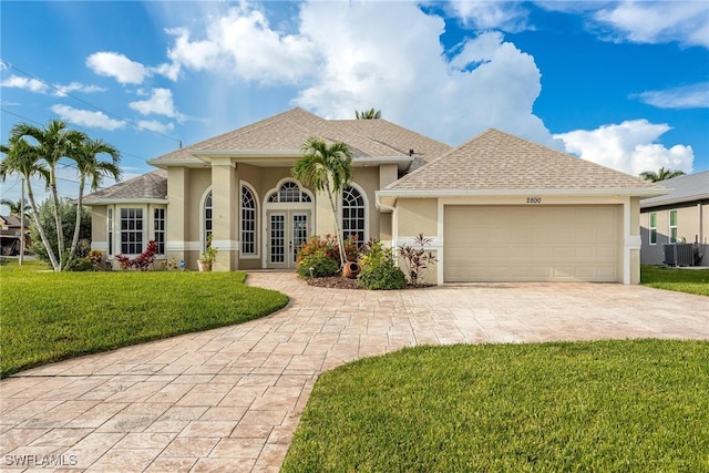 view of front facade with a garage, french doors, central AC, and a front lawn