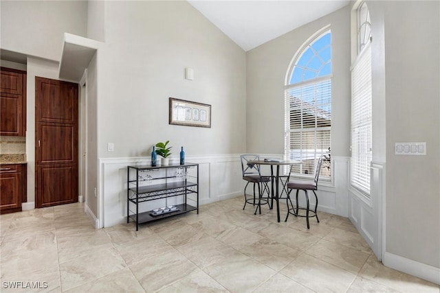 dining room featuring light tile patterned floors, a wealth of natural light, and high vaulted ceiling