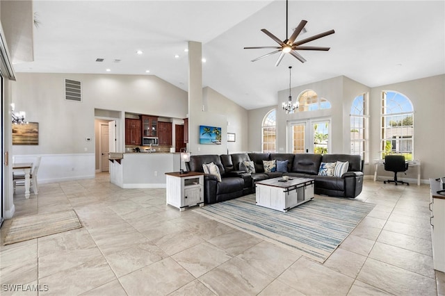 tiled living room featuring high vaulted ceiling and ceiling fan with notable chandelier