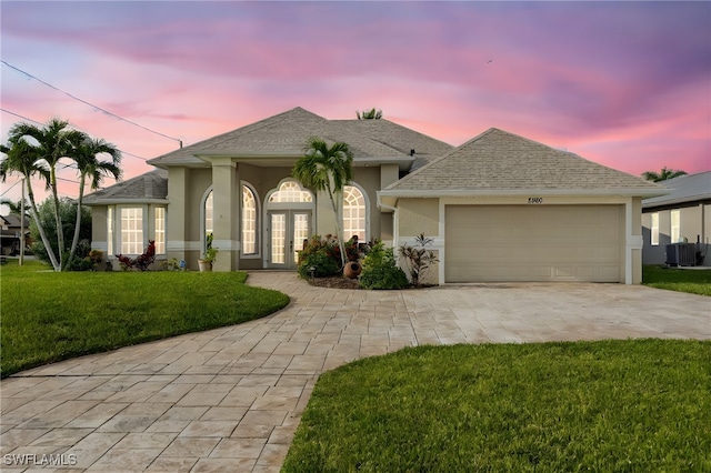 view of front of house featuring central air condition unit, french doors, a garage, and a yard