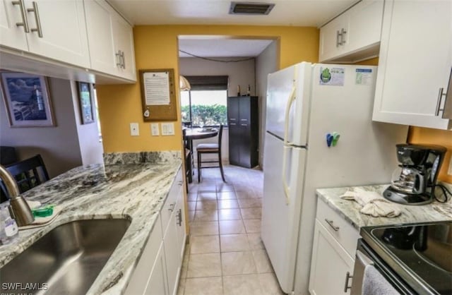 kitchen featuring sink, light stone counters, white cabinetry, and light tile patterned floors