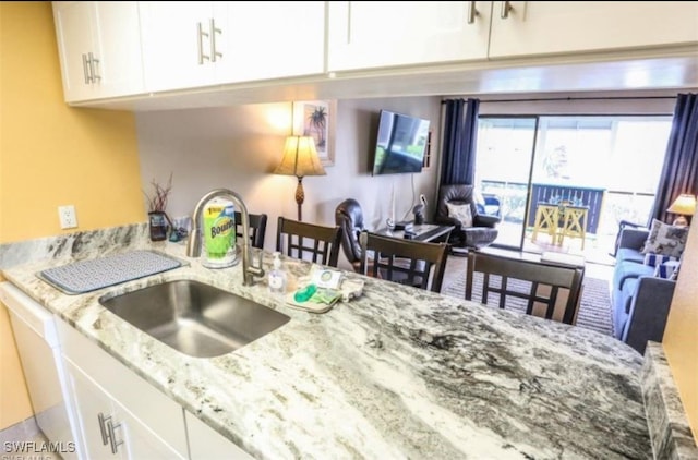 kitchen with sink, white cabinetry, and light stone countertops