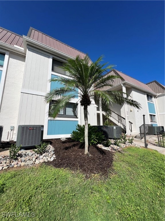 view of side of property with a lawn and central AC unit