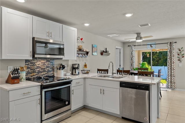 kitchen with stainless steel appliances, sink, white cabinets, kitchen peninsula, and ceiling fan