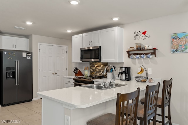 kitchen with a kitchen breakfast bar, light tile patterned flooring, appliances with stainless steel finishes, kitchen peninsula, and white cabinets