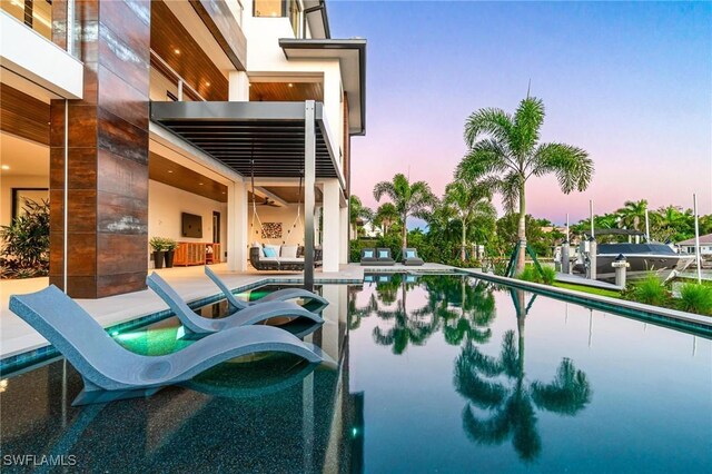 pool at dusk featuring a dock and a patio