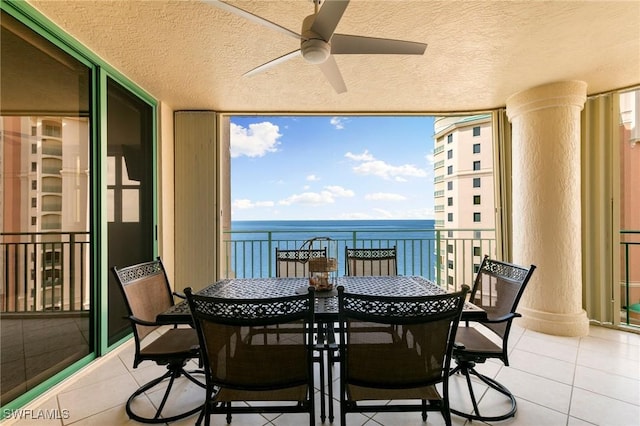 exterior space featuring ornate columns, a water view, and ceiling fan