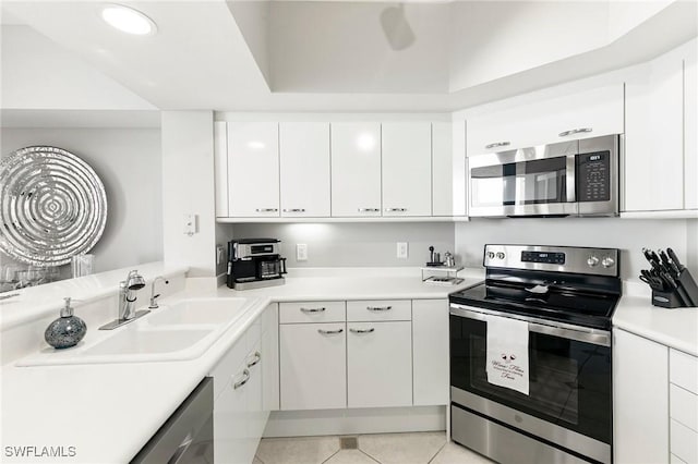 kitchen featuring white cabinets, appliances with stainless steel finishes, light tile patterned floors, and sink