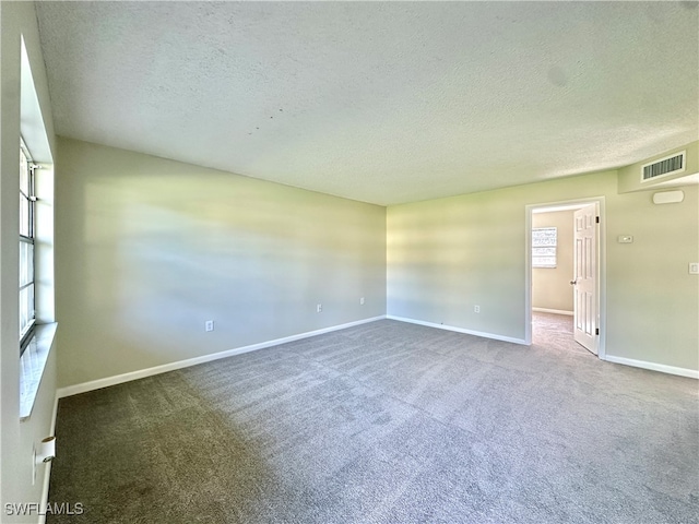 empty room with carpet flooring and a textured ceiling