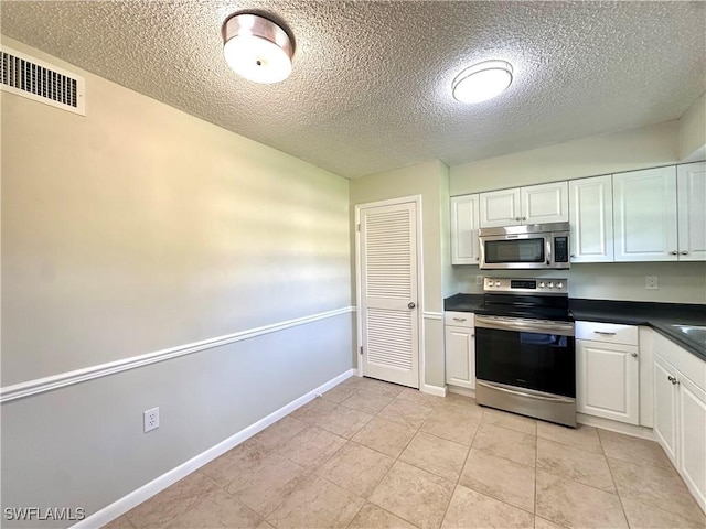 kitchen featuring white cabinetry, appliances with stainless steel finishes, light tile patterned flooring, and a textured ceiling