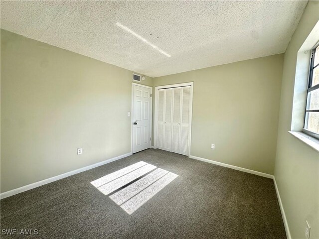 spare room featuring a textured ceiling and carpet