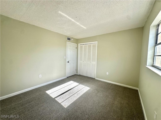 unfurnished bedroom featuring a closet, a textured ceiling, and dark colored carpet