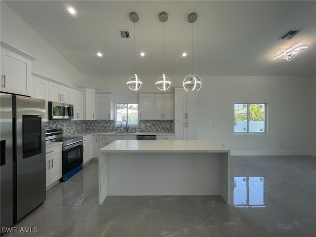 kitchen featuring stainless steel appliances, pendant lighting, decorative backsplash, a healthy amount of sunlight, and dark tile patterned flooring