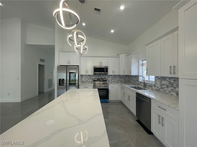 kitchen with tasteful backsplash, appliances with stainless steel finishes, hanging light fixtures, light stone counters, and sink