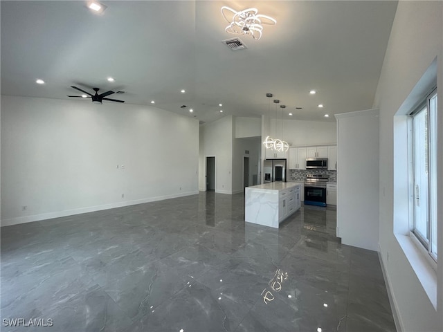 unfurnished living room with ceiling fan with notable chandelier, tile patterned flooring, and vaulted ceiling