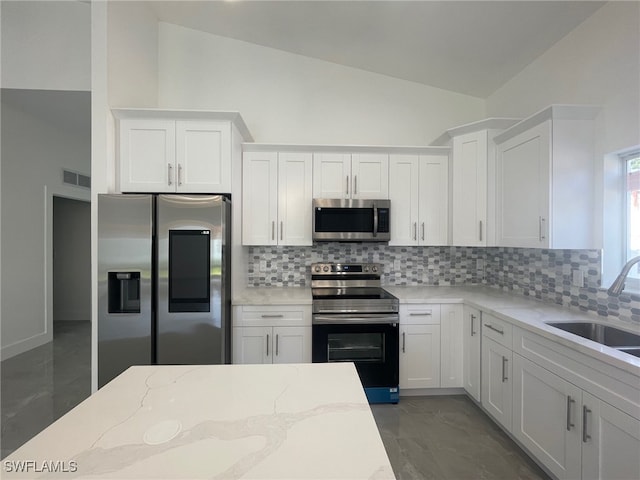 kitchen with backsplash, stainless steel appliances, and white cabinetry