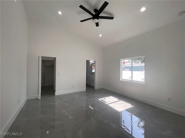 unfurnished room with high vaulted ceiling, dark tile patterned flooring, and ceiling fan