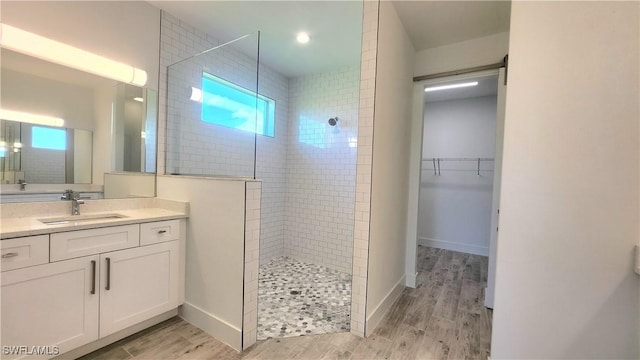 bathroom with vanity, a tile shower, wood-type flooring, and a wealth of natural light