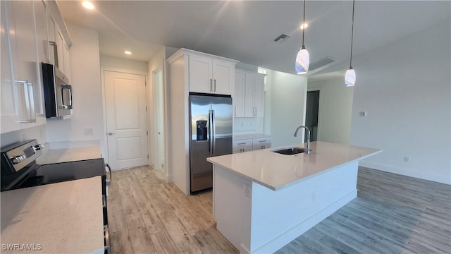 kitchen featuring white cabinetry, sink, hanging light fixtures, stainless steel appliances, and light hardwood / wood-style floors