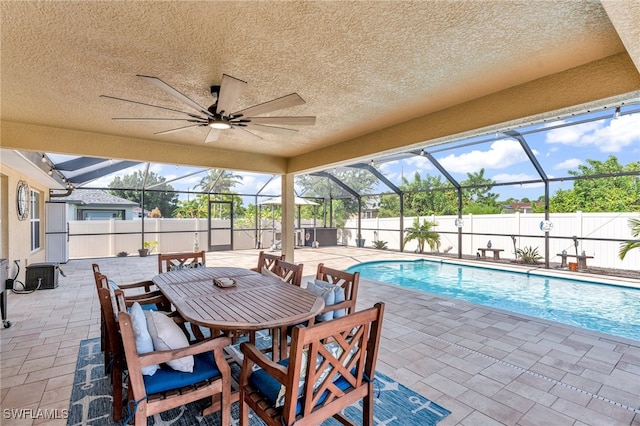 view of pool with glass enclosure, ceiling fan, and a patio