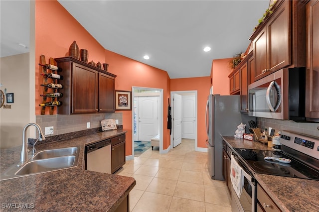 kitchen with appliances with stainless steel finishes, vaulted ceiling, backsplash, sink, and light tile patterned flooring