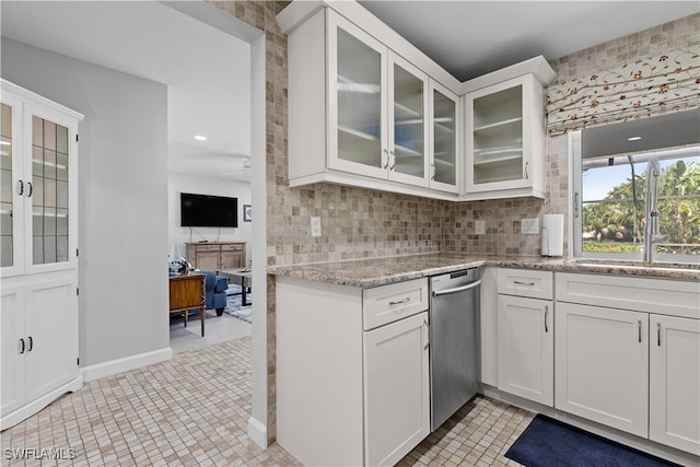 kitchen with backsplash, stainless steel dishwasher, white cabinetry, and light tile patterned floors