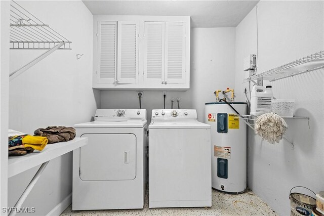 laundry area featuring washing machine and dryer, water heater, and cabinets