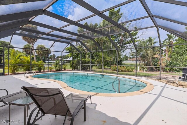 view of pool featuring glass enclosure and a patio