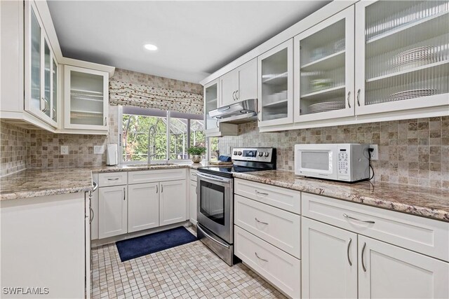 kitchen featuring decorative backsplash, white cabinets, light tile patterned floors, stainless steel range with electric stovetop, and sink