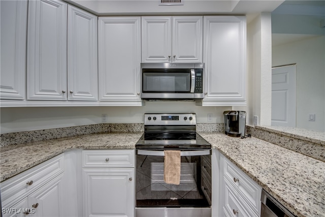 kitchen with light stone countertops, white cabinetry, and stainless steel appliances