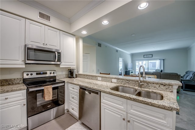 kitchen with light stone countertops, appliances with stainless steel finishes, sink, kitchen peninsula, and white cabinetry