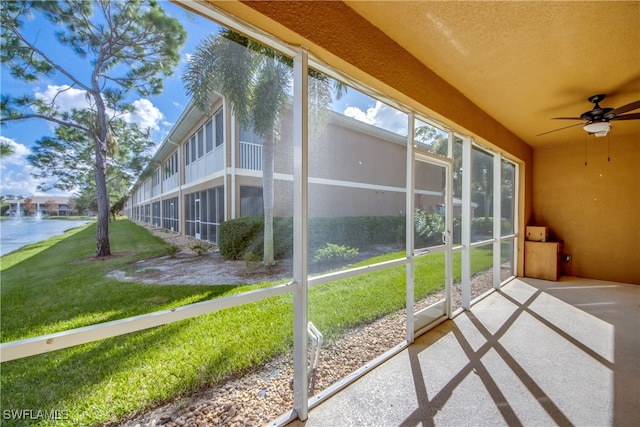 unfurnished sunroom with a water view and ceiling fan