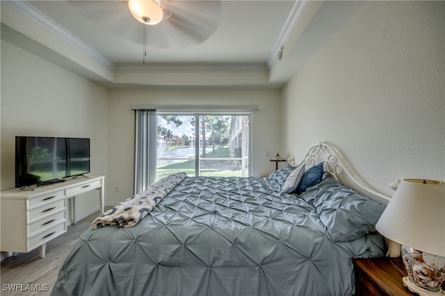 bedroom with ornamental molding, a tray ceiling, light wood-type flooring, and ceiling fan