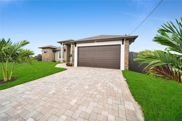 prairie-style house featuring a front yard, decorative driveway, fence, and an attached garage