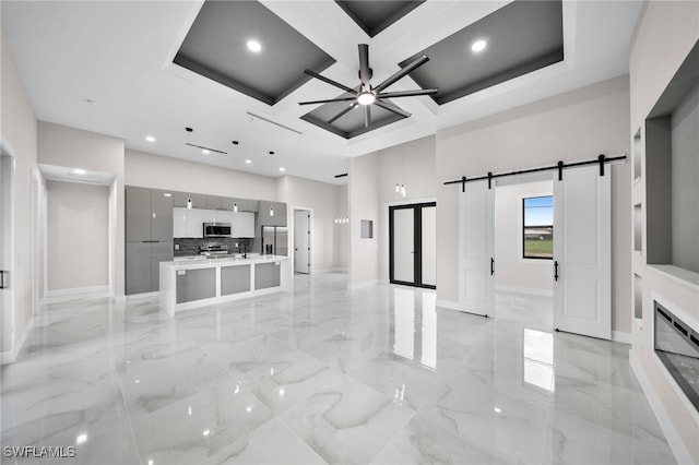 unfurnished living room featuring ceiling fan, beam ceiling, a barn door, light tile patterned floors, and coffered ceiling